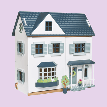 Charming wooden dolls house with blue roof and detailed shutters.