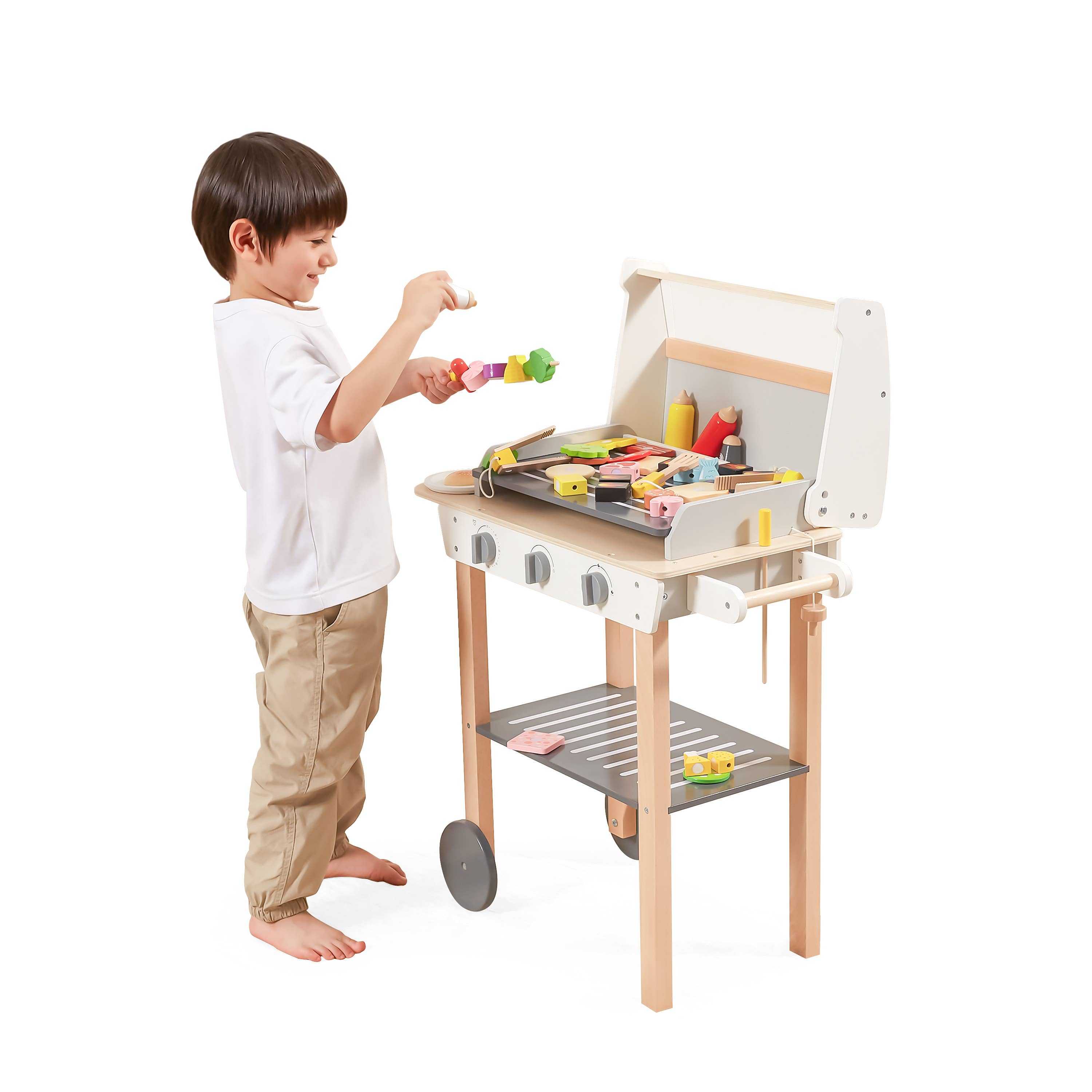Child playing with a wooden BBQ play set, grilling colorful wooden food pieces. Encourages imaginative play and motor skill development.