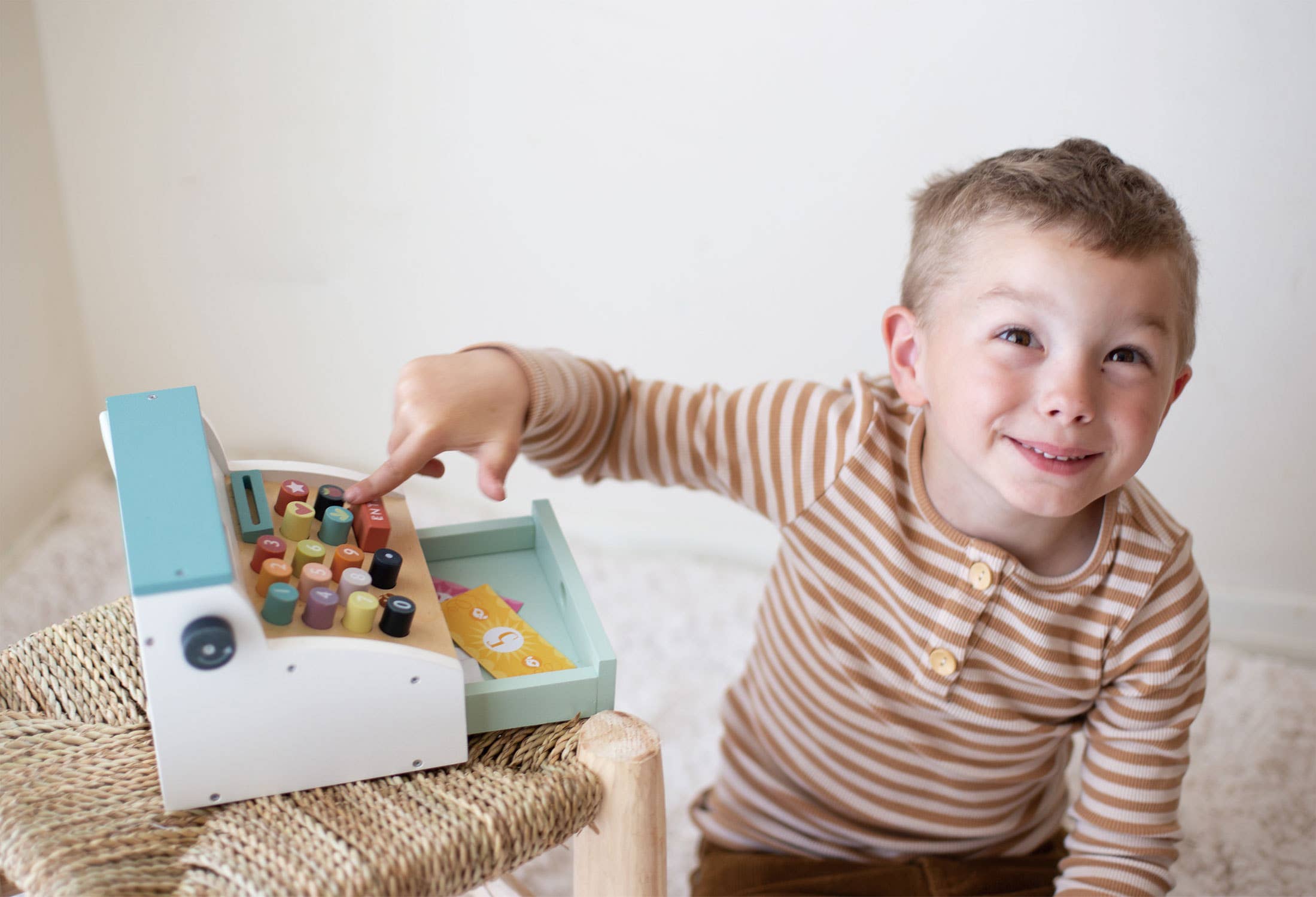Smiling boy playing with Wooden Role Play Shop Till & Scanner - General Stores Till, enjoying pretend shopping and learning numbers.