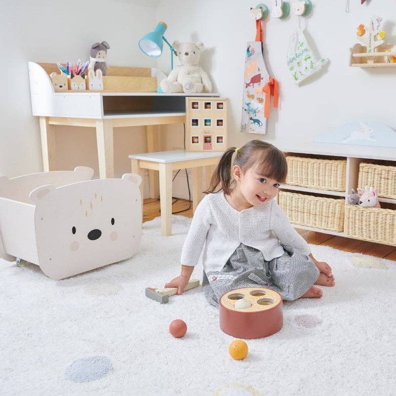 Toddler playing in a nursery with the Childs Wooden Drawing Desk and Stool in the background, blending into a cozy learning space.