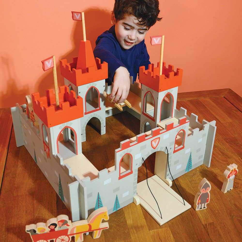 Child playing with Mentari Wooden King's Castle Toy Play Set on a wooden table, showcasing interactive features and character figures for creative storytelling.