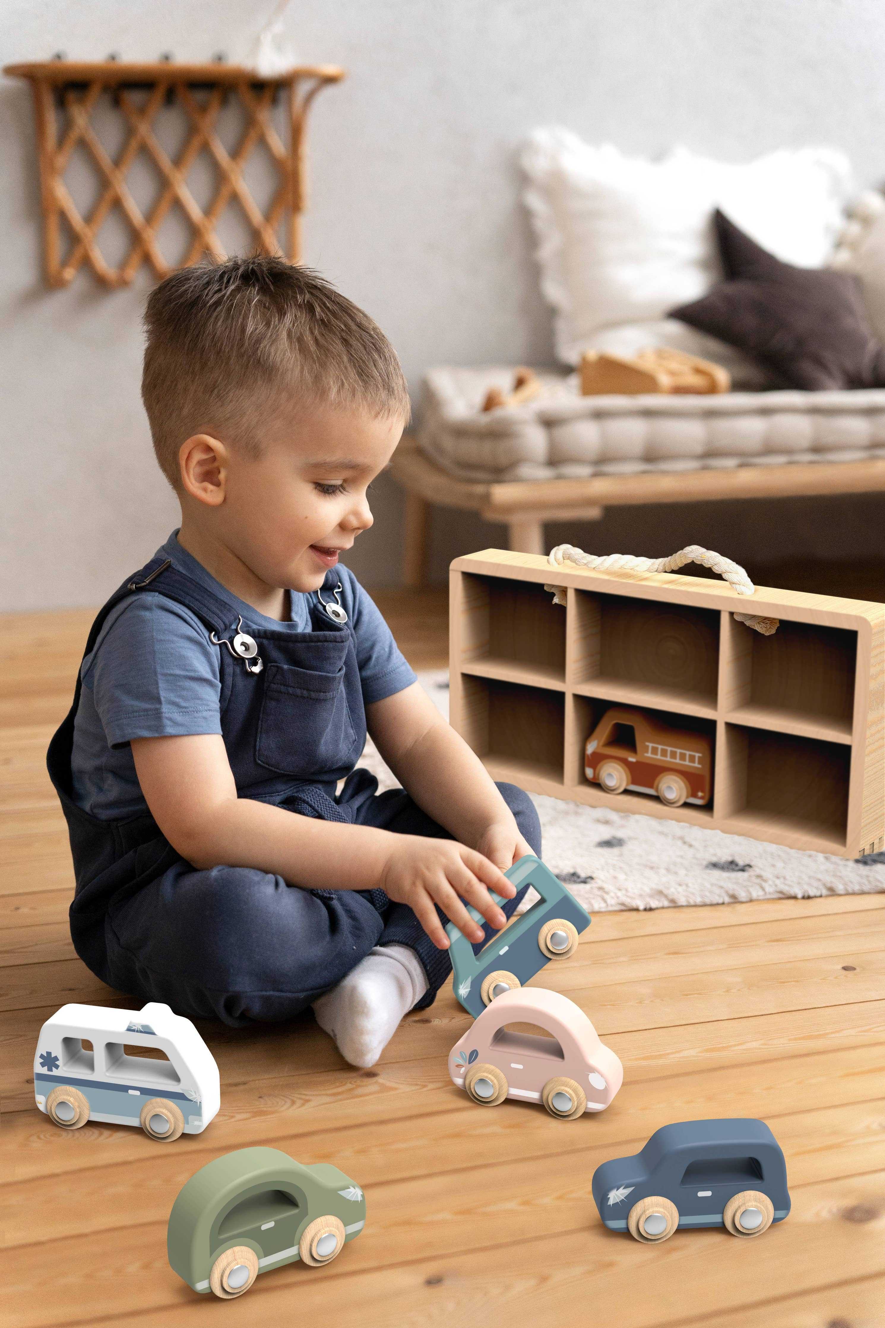 Toddler playing with Speedy Monkey Wooden Car Display Case and 6 wooden vehicles, encouraging motor skills and imaginative play in a cozy room.