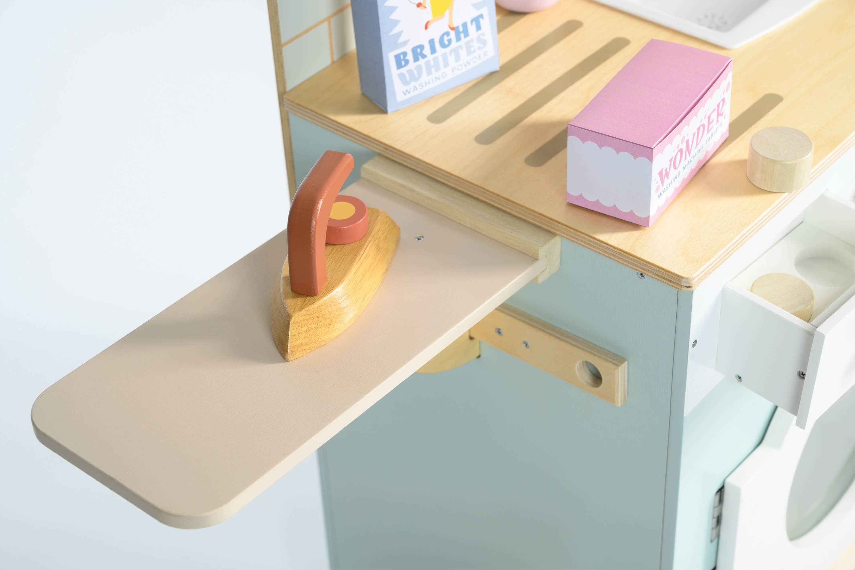 Close-up of Tender Leaf Wooden Laundrette's ironing board with wooden iron and folded towel for pretend play.