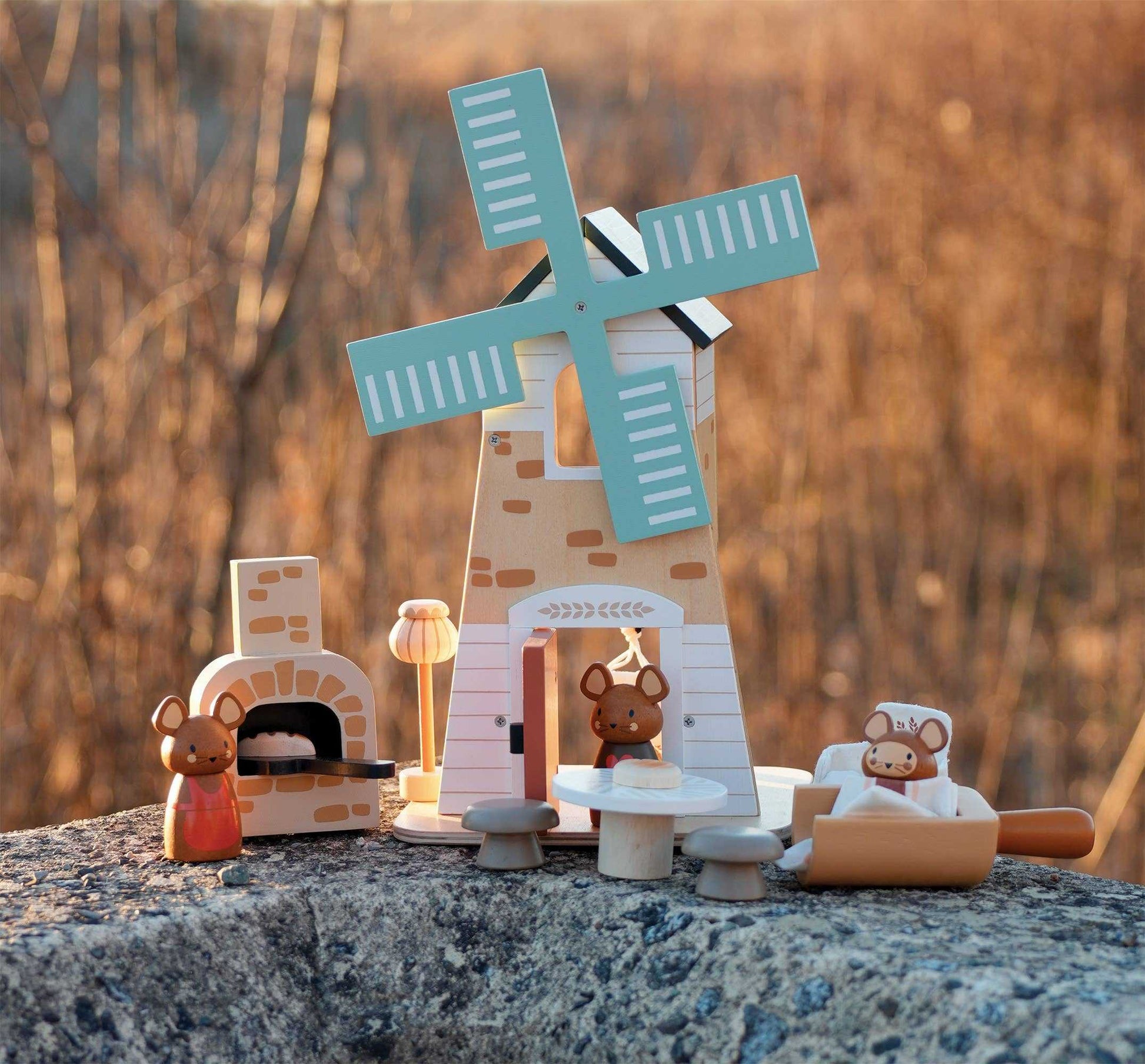 Penny Windmill Character Play Set Wooden Toy arranged on a stone surface at sunset, highlighting detailed wooden mice and accessories.