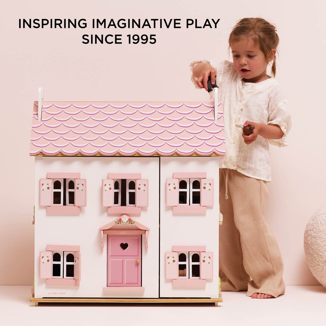 Le Toy Van Sophie's Wooden Dolls House with pink roof, floral shutters, and heart-shaped door, made from FSC-certified wood.