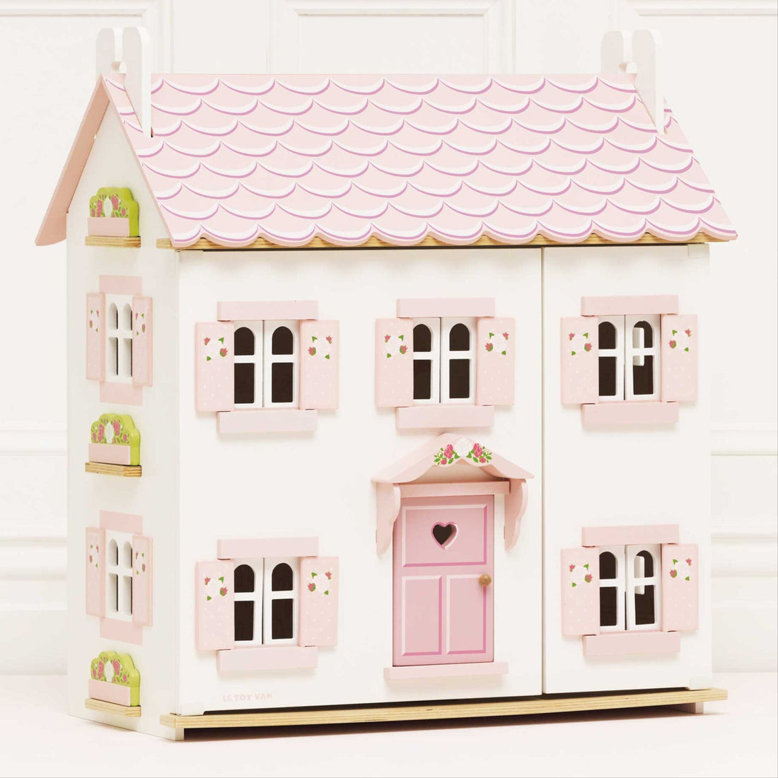Le Toy Van Sophie's Wooden Dolls House with pink roof, floral shutters, and heart-shaped door, made from FSC-certified wood.