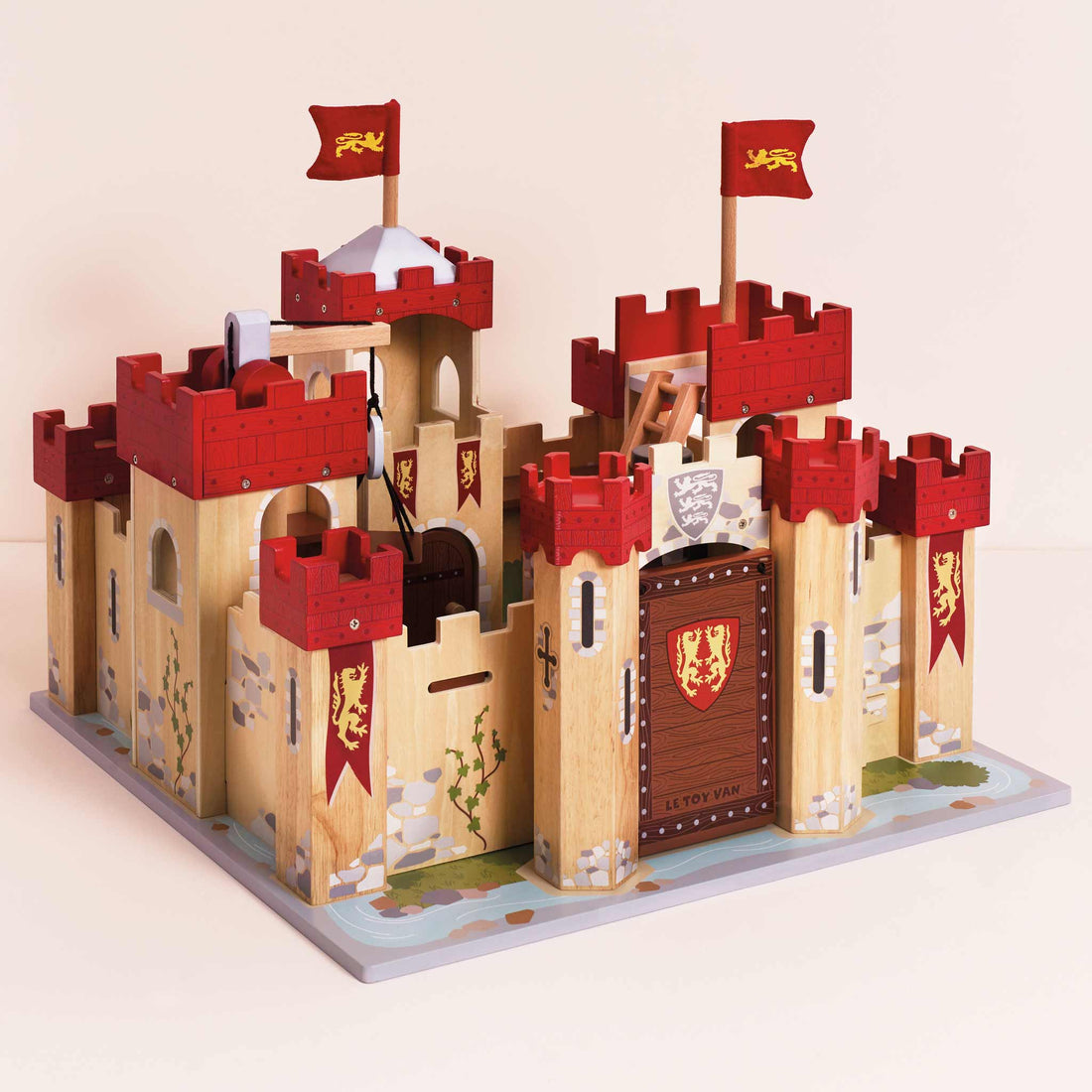 Le Toy Van Lionheart Wooden Play Castle with red turrets, drawbridge, and medieval design, ideal for imaginative pretend play for kids age 3+.
