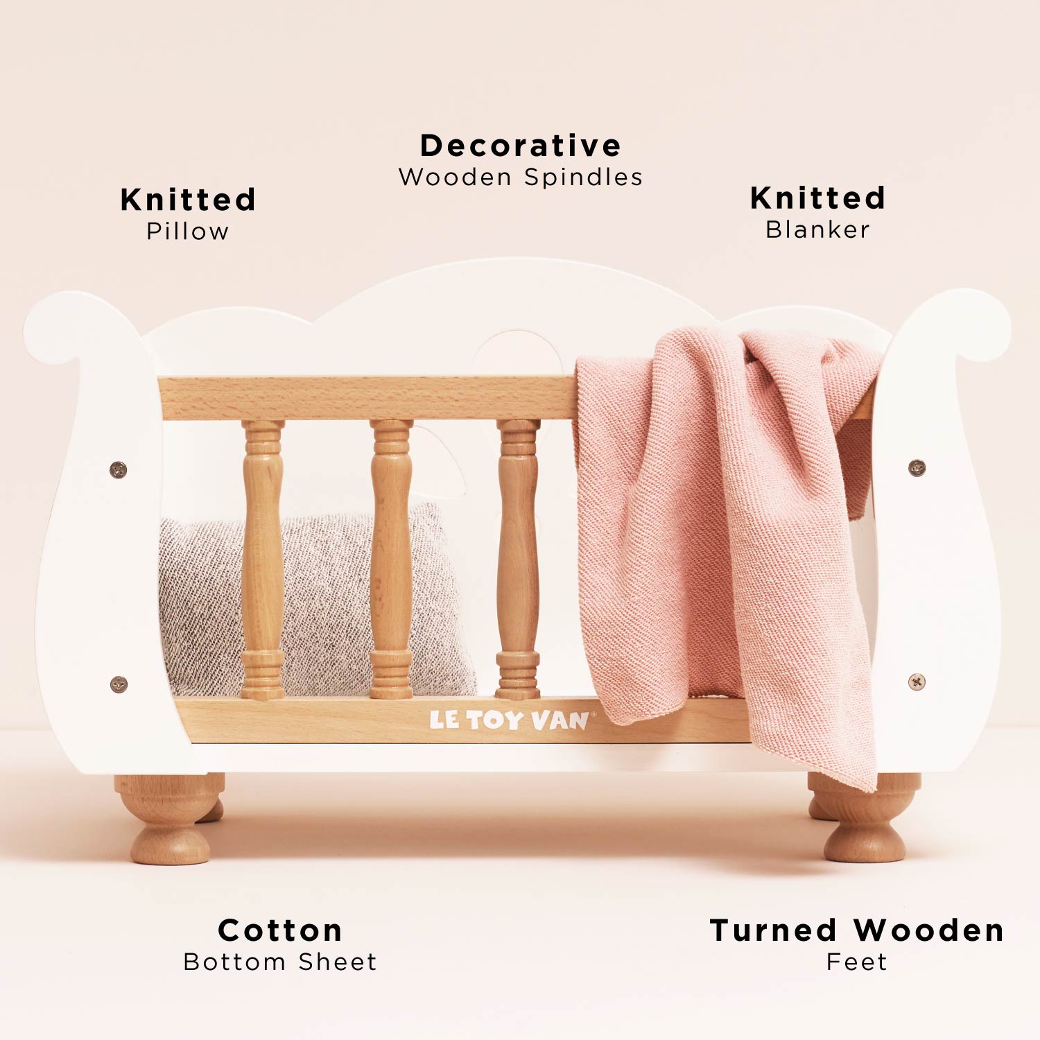 Close-up of Ley Toy Van Dolls Cot showing knitted pillow, blanket, cotton sheet, and decorative wooden spindles for doll nursery role play.