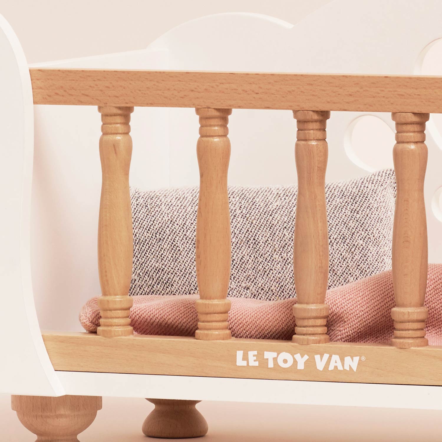 Detailed view of Ley Toy Van Dolls Cot wooden spindles and soft bedding, showcasing quality craftsmanship and FSC-certified materials.