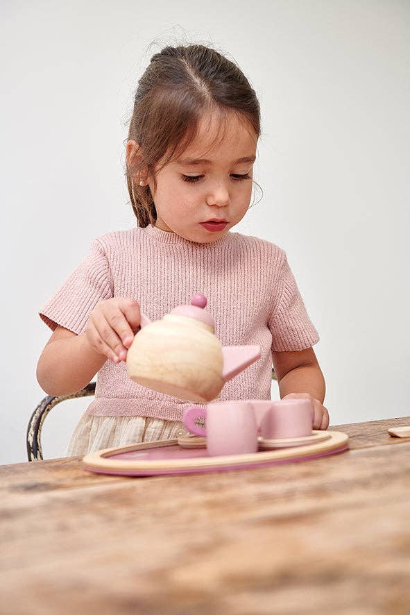 Young child engaging in pretend play with the Birdie Tea Tray Set - Wooden Role Play Toy, pouring tea from the wooden teapot into matching cups.