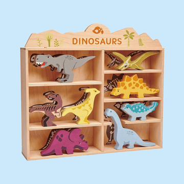 Wooden shelf display with labeledDINOSAURS" sign, holding colorful wooden dinosaur figurines including T-Rex, Triceratops, Stegosaurus, and others in individual compartments.