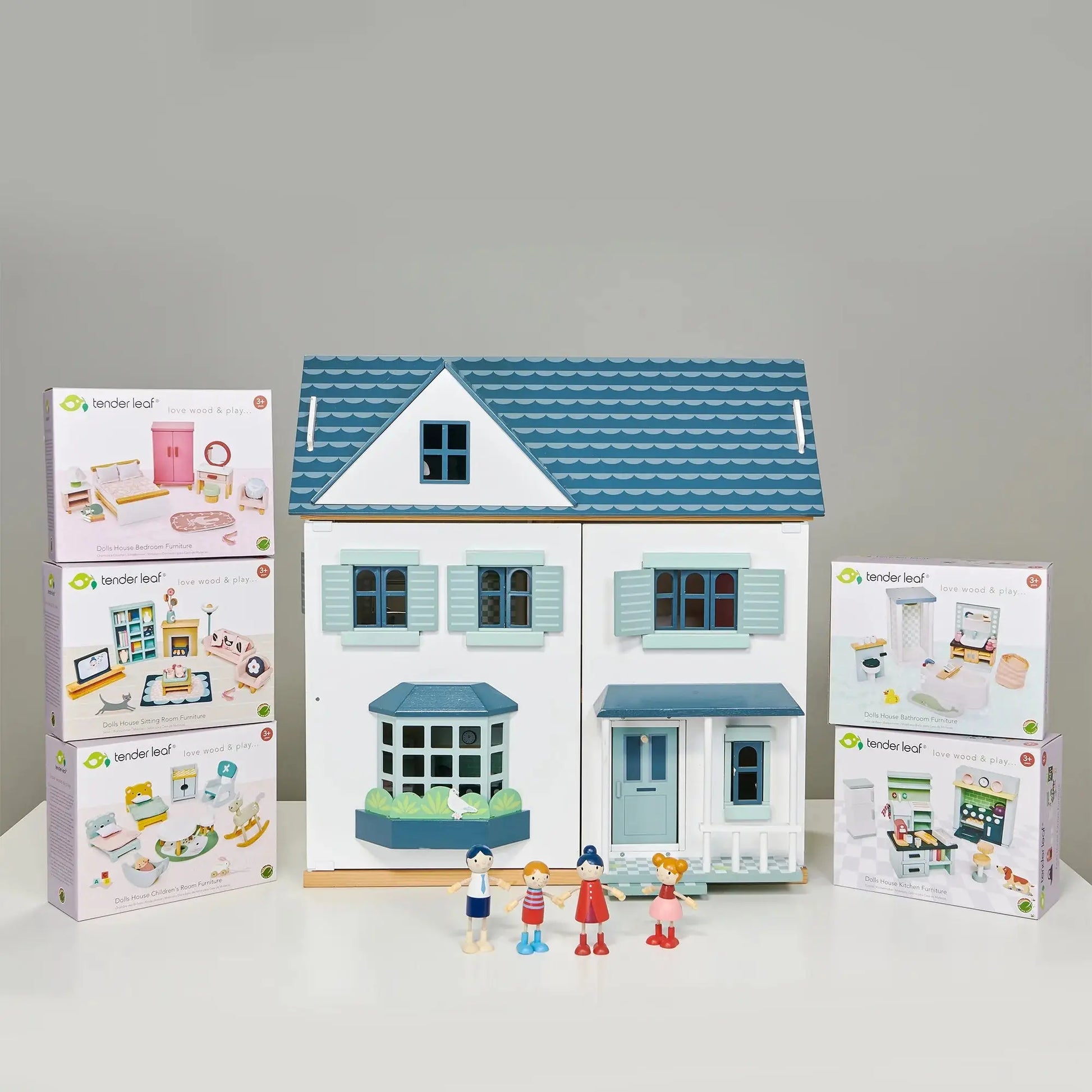 Dovetail House Wooden Dolls House with Furniture Bundle, featuring a double-fronted two-story dollhouse with a blue roof and pastel shutters, alongside a doll family and furniture sets.